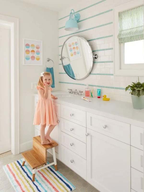 Kid-Friendly Bathroom with Teal Tile Accents and Colorful Striped Rug