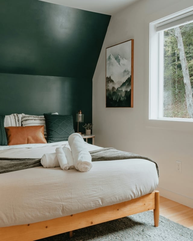 Light Wood Platform Bed Against Sloped Forest Green Wall