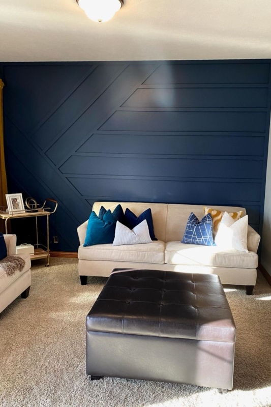 Living Room with Navy Blue Geometric Accent Wall and Tufted Ottoman
