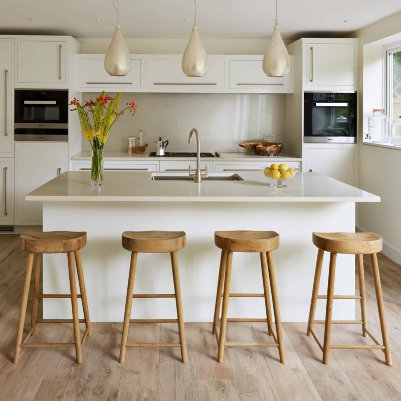 Minimalist Kitchen with Carved Wood Barstools and Teardrop Pendants