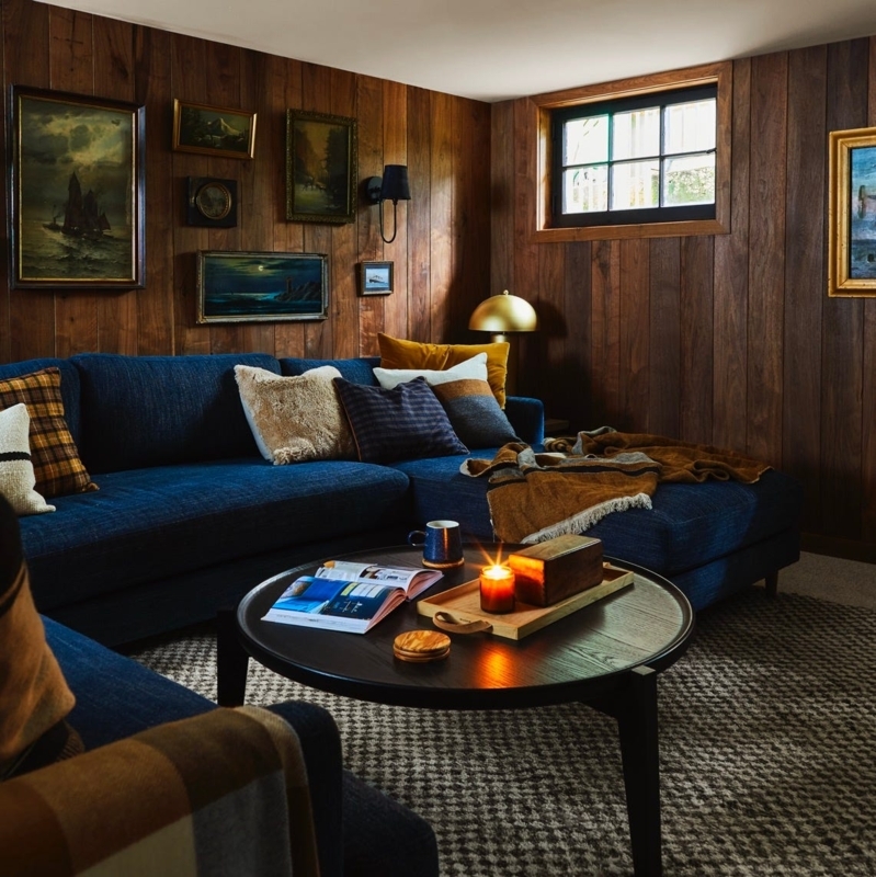 Navy Blue Sectional in Moody Basement with Dark Wood Paneling