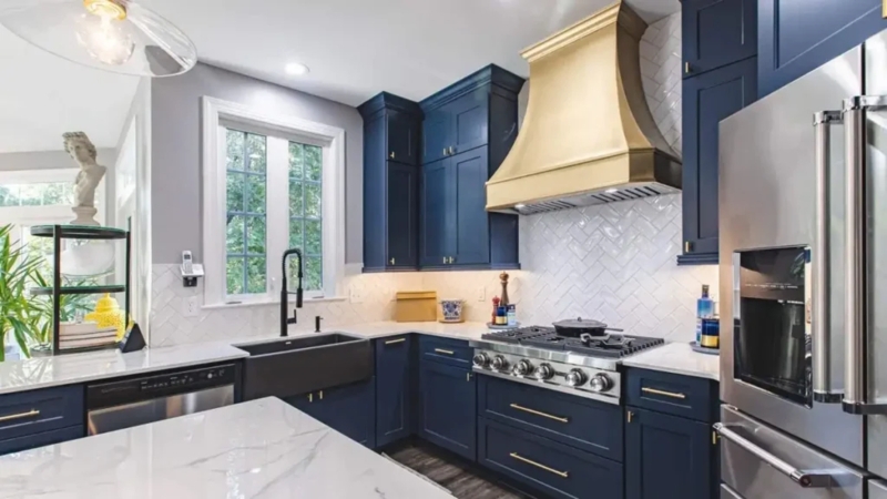 Navy Shaker Cabinets paired with a Bold Gold Range Hood Design