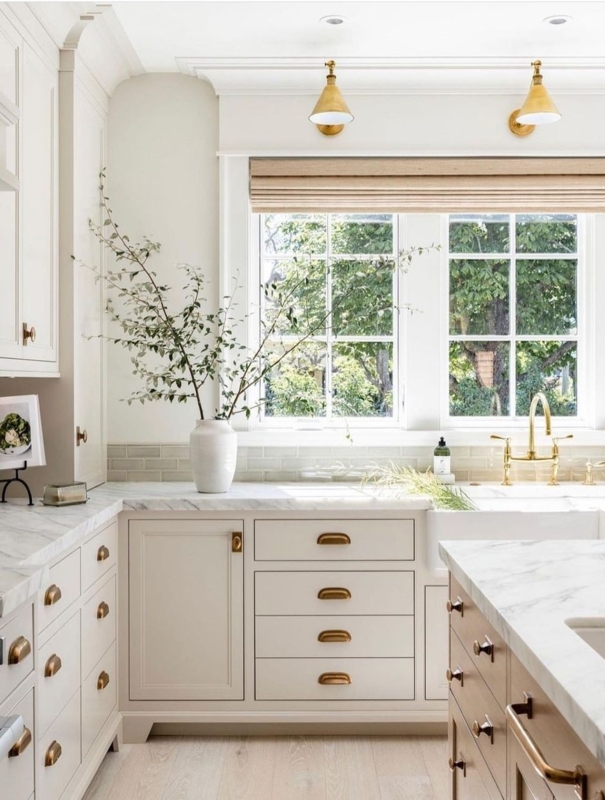 Off-White Kitchen with Brass Hardware and Gold Sconces over Window