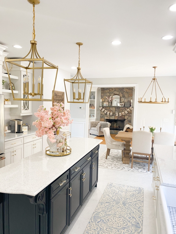 Open Concept White and Gold Kitchen with Dark Island and Stone Fireplace