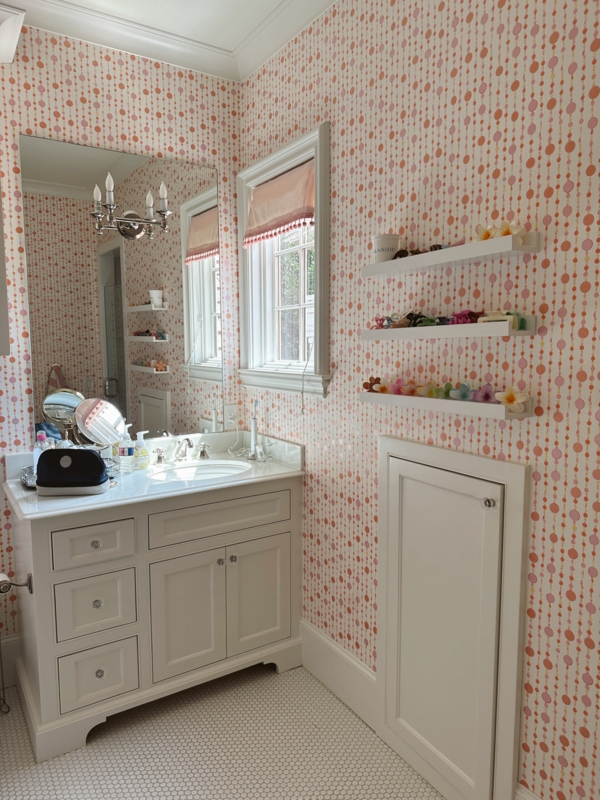 Playful Bathroom Design with pink beaded wallpaper and pom-pom trim shade.