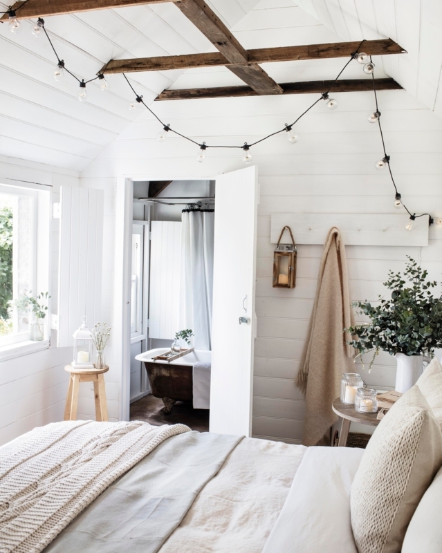 Rustic Attic Bed with Exposed Beams, Shiplap Walls, and String Lights