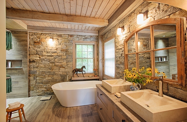 Rustic Stone Wall Bathroom Design with Freestanding Tub and Arched Mirror