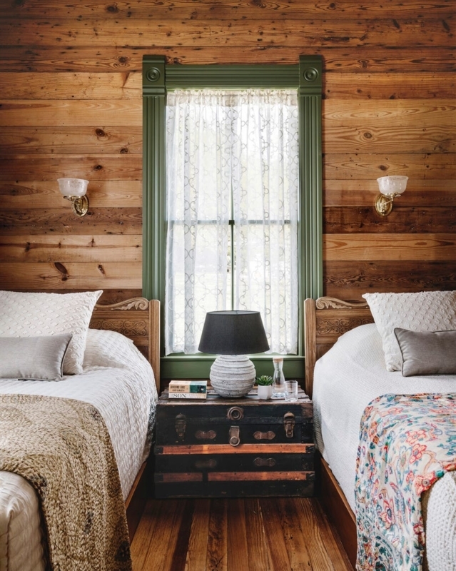 Rustic Twin Bedroom with Wood Paneling and Vintage Trunk Nightstand