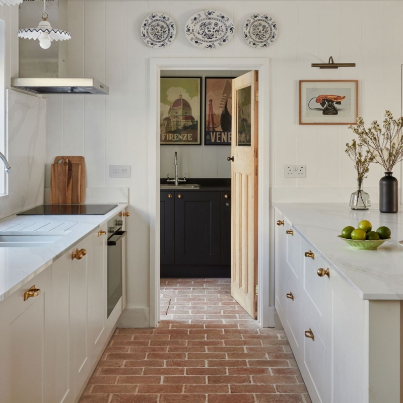 Small Kitchen with Red Brick Flooring and White Cabinets Gold Hardware