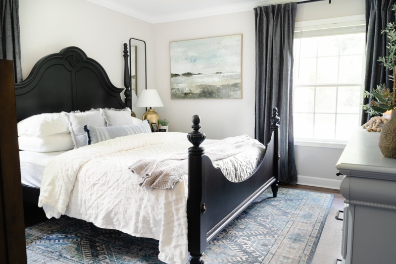 Traditional Black Bed Frame with Blue Distressed Rug and Landscape Art