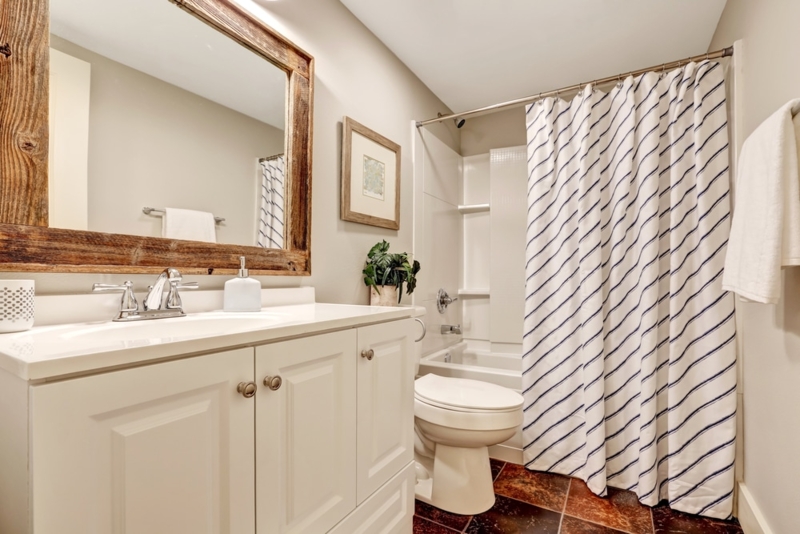 Transitional Bathroom featuring white shaker vanity and rustic wood mirror.