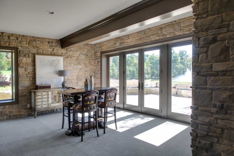 Transitional Lounge with Rugged Stone Veneer Walls and Large French Doors