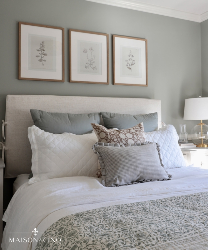 Upholstered Bed with Botanical Prints Above and Sage Green Wall Paint