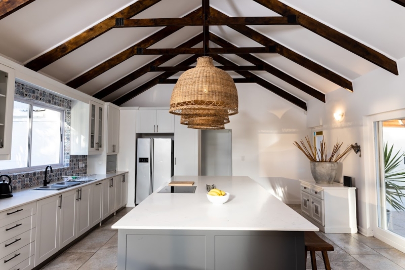 Vaulted Kitchen Ceiling with Dark Wood Trusses and Rattan Pendant