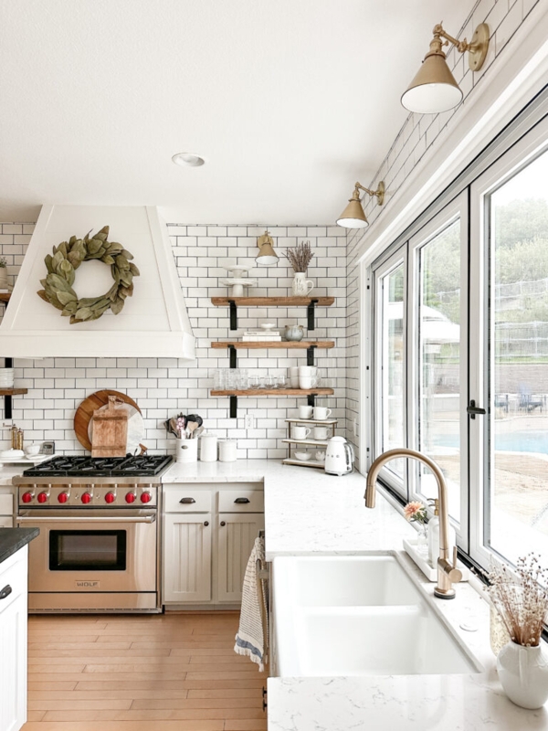 White Kitchen With Wood Shelves And Brass Wall Sconces