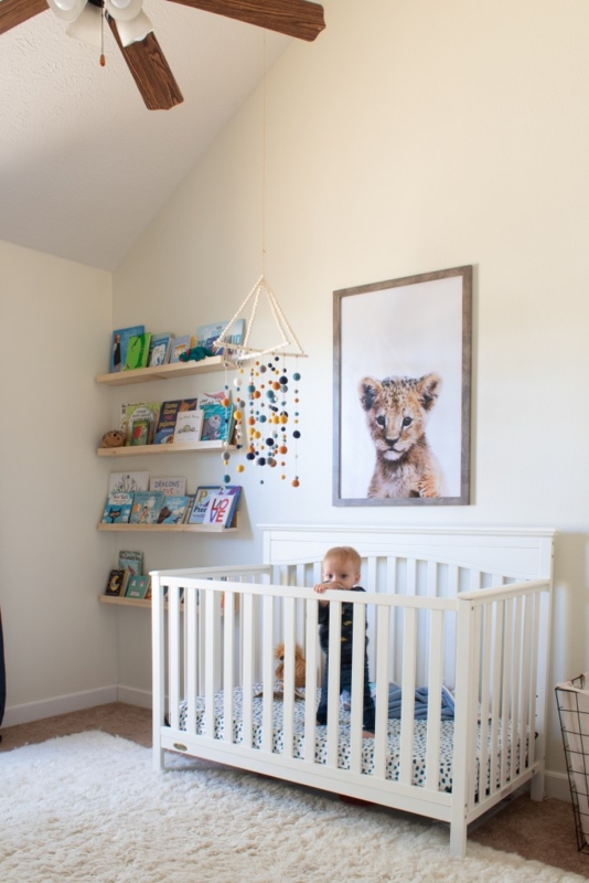 White Slatted Crib in Airy Neutral Nursery with Lion Cub Wall Art