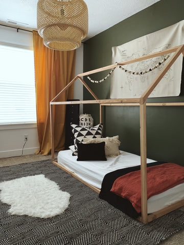 Wooden House Shaped Floor Bed Against Green Accent Wall