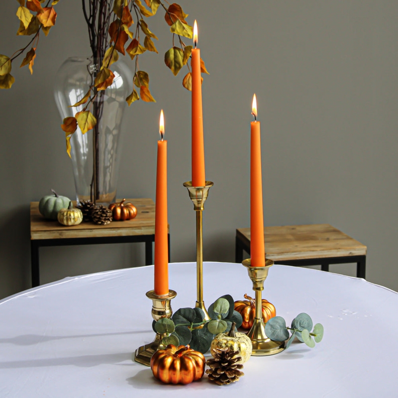 Vibrant Orange Taper Candles with Varying Height Holders for Autumn