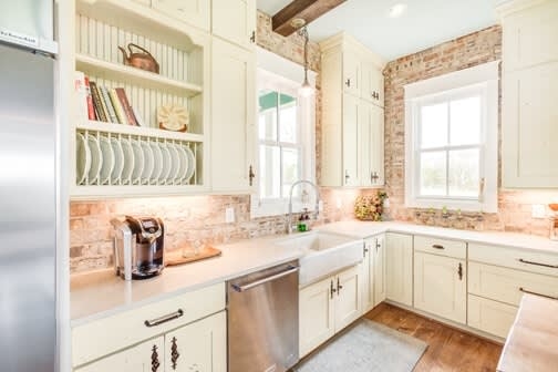 Farmhouse Kitchen with Exposed Brick Backsplash and Integrated Plate Rack