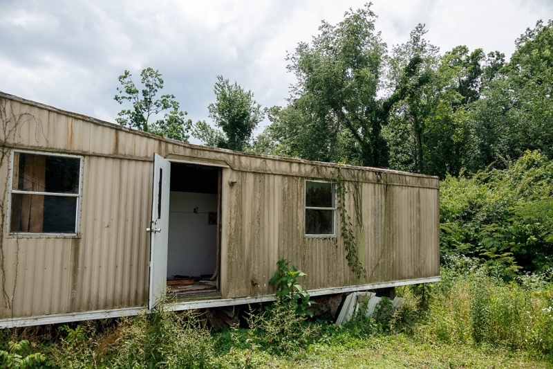 Abandoned Manufactured Home with Overgrown Vines and Weathered Siding