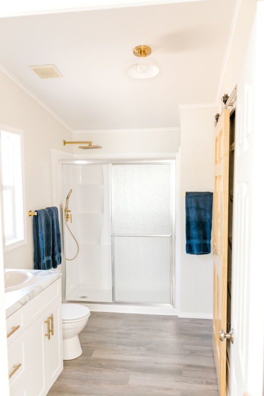 Bright Bathroom Remodel with Brushed Gold Hardware and Barn Door