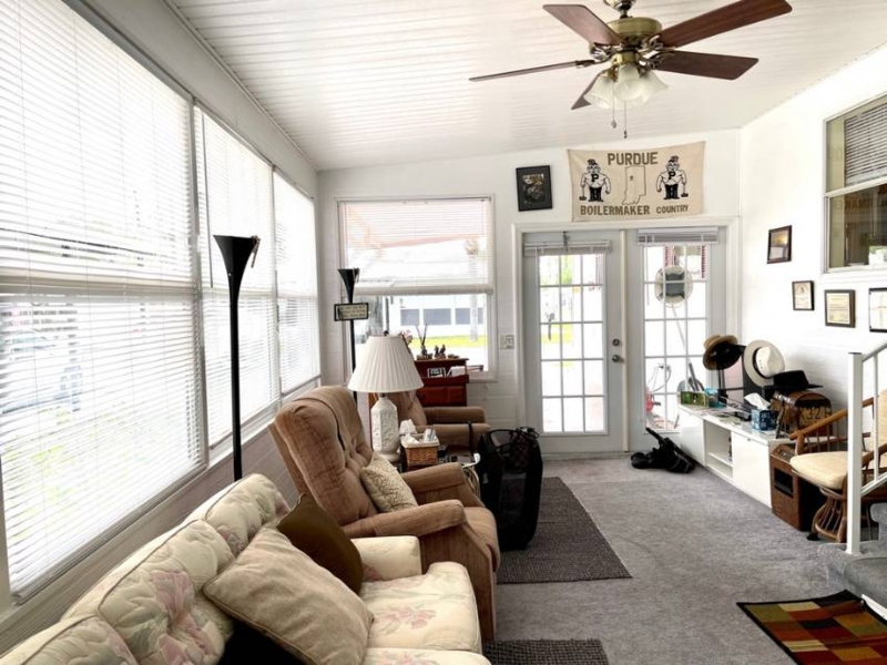 Bright Sunroom with Slatted Ceiling, Wraparound Windows, and Floral Sofa