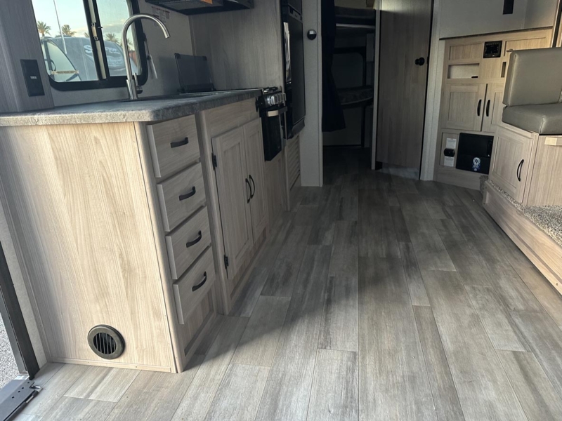 Compact Mobile Home Kitchen Layout: Light Gray Plank Floors & Wood Cabinets