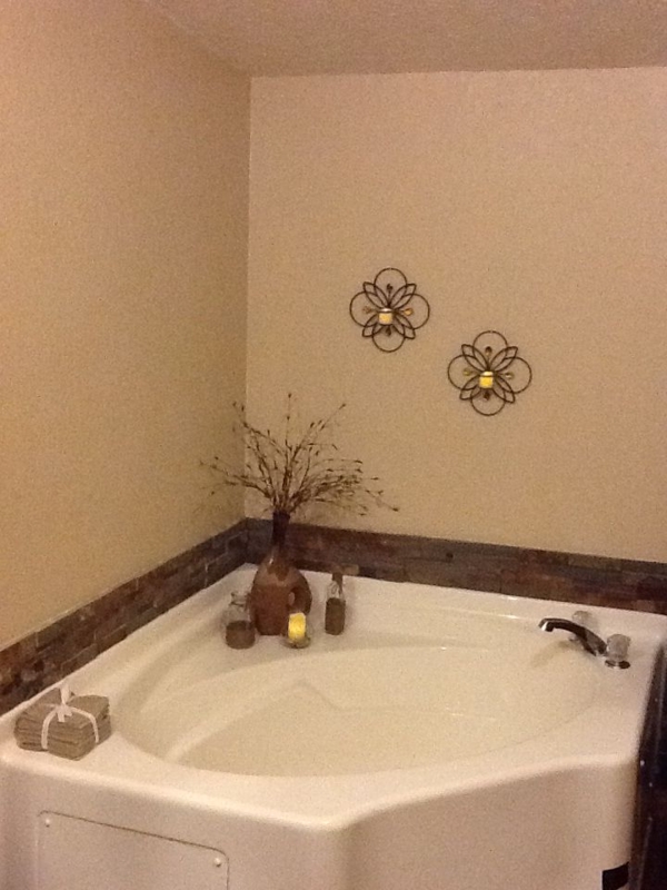 Corner Bathtub with Stone Backsplash Ledge and Rustic Decor
