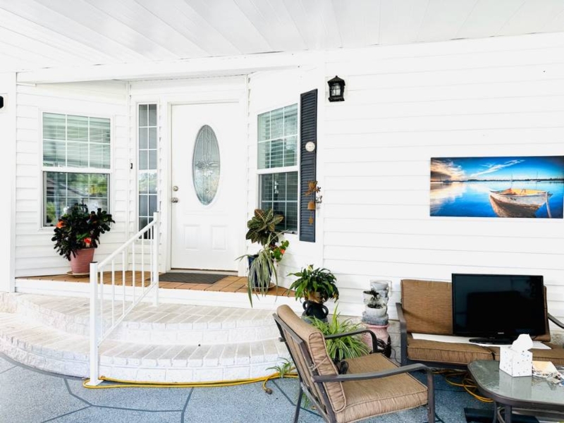Covered Porch Entryway: White Vinyl Siding, Lounge Seating, & Plants