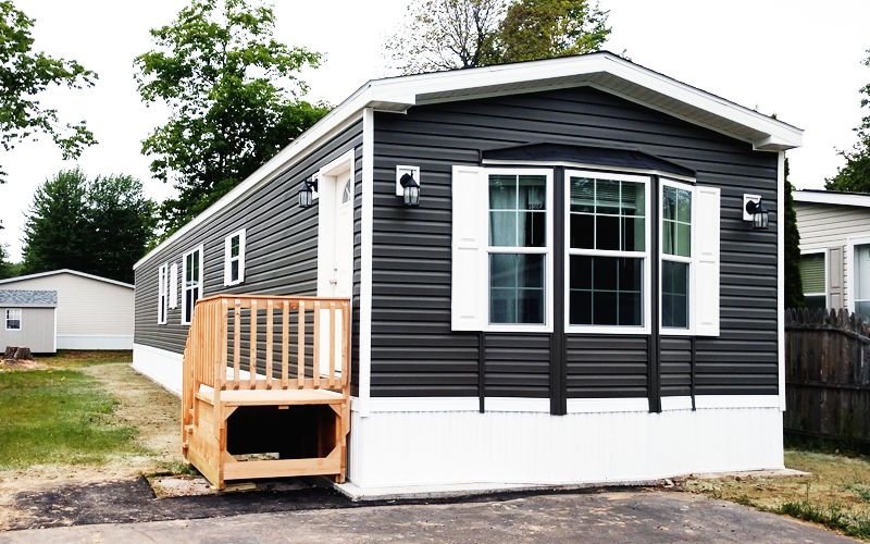 Dark Siding Mobile Home Exterior with Bay Window and Wooden Stairs