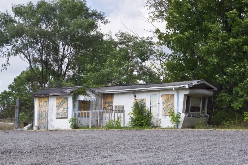Dilapidated Mobile Home with Graffiti Warnings and Boarded Windows