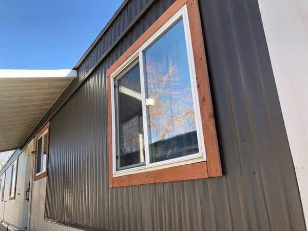 Exterior Sliding Window with Wide Wood Trim on Dark Metal Siding