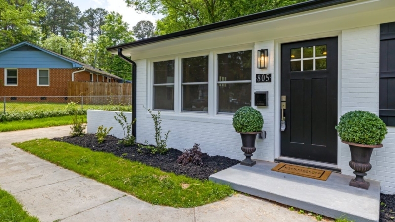 Farmhouse Entryway with Symmetrical Topiary Urns and Black Shutters