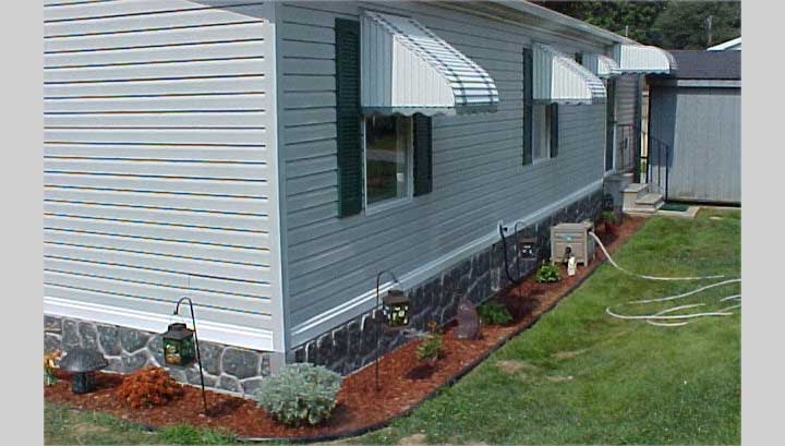 Faux Stone Mobile Home Skirting with Striped Awnings and Mulch Border