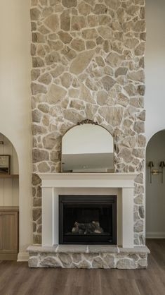 Floor to Ceiling Stone Fireplace with White Mantel and Arched Mirror