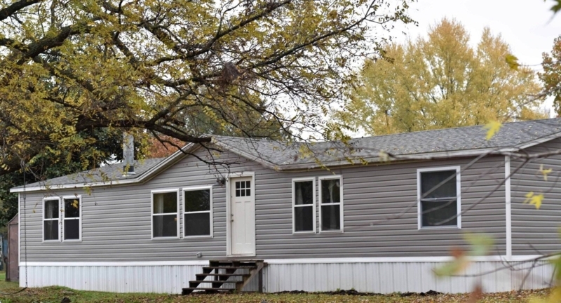 Gray Double-Wide Mobile Home with White Skirting & Wood Steps