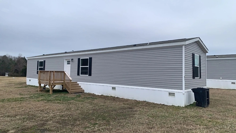 Gray Vinyl Siding Mobile Home with Small Wooden Deck and Shutters