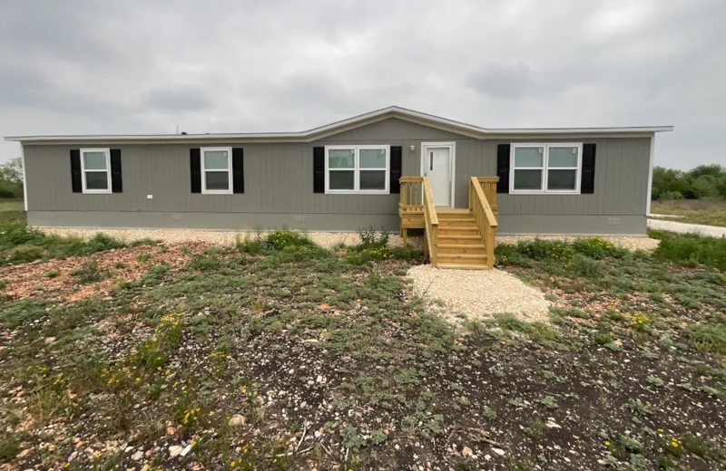 Manufactured Home with Gray Siding, Black Shutters, and Wooden Porch