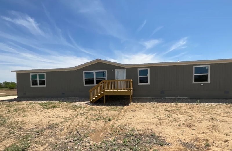 Manufactured Home with Grey Vertical Siding and Wooden Front Deck