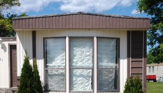 Manufactured Home With Triple Bay Window And Brown Roof Overhang