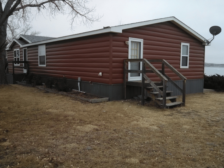 Mobile Home Exterior: Rustic Red Log Siding & Grey Skirting.