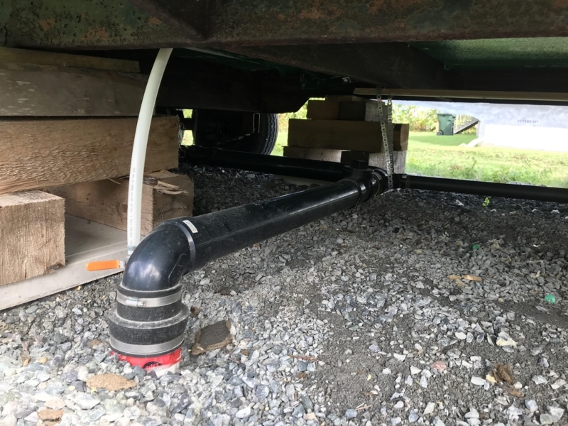 Mobile Home Undercarriage Plumbing Installation with Wooden Supports