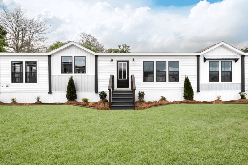 Modern Mobile Home Exterior: Black Trim & Symmetrical Evergreens