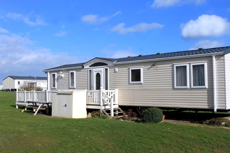 Modern Mobile Home Exterior with Charcoal Roof and White Deck