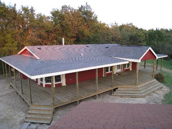 Red Mobile Home Exterior with Rustic Unfinished Wood Wrap Around Porch