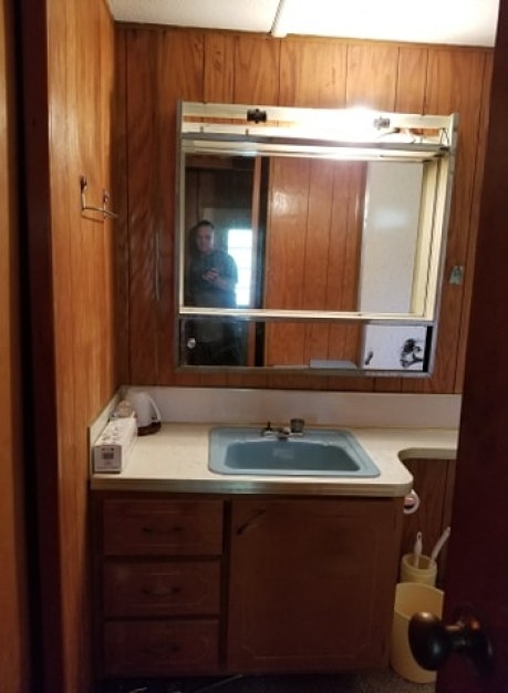 Retro Mobile Home Bathroom with Wood Paneling and Blue Drop-In Sink