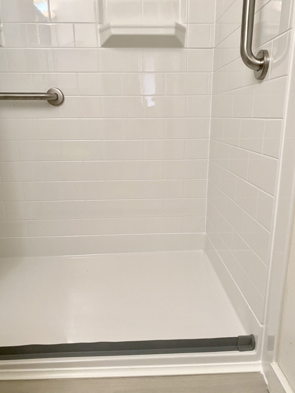 Shower Stall with Flexible Threshold, Grab Bars, and Subway Tile.