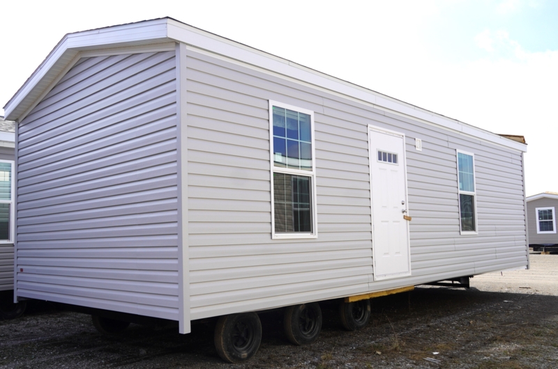 Small Mobile Home on Triple-Axle Trailer with Gray Siding