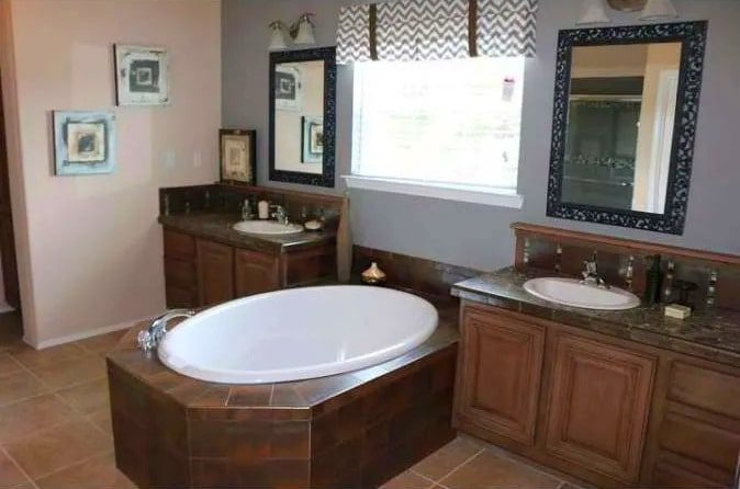 Spacious Bathroom: Oval Soaking Tub & Dual Wood-Toned Vanities