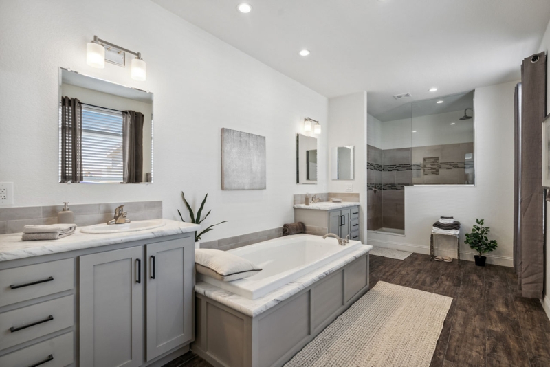 Spacious Transitional Bathroom with Gray Vanities and Drop-In Tub